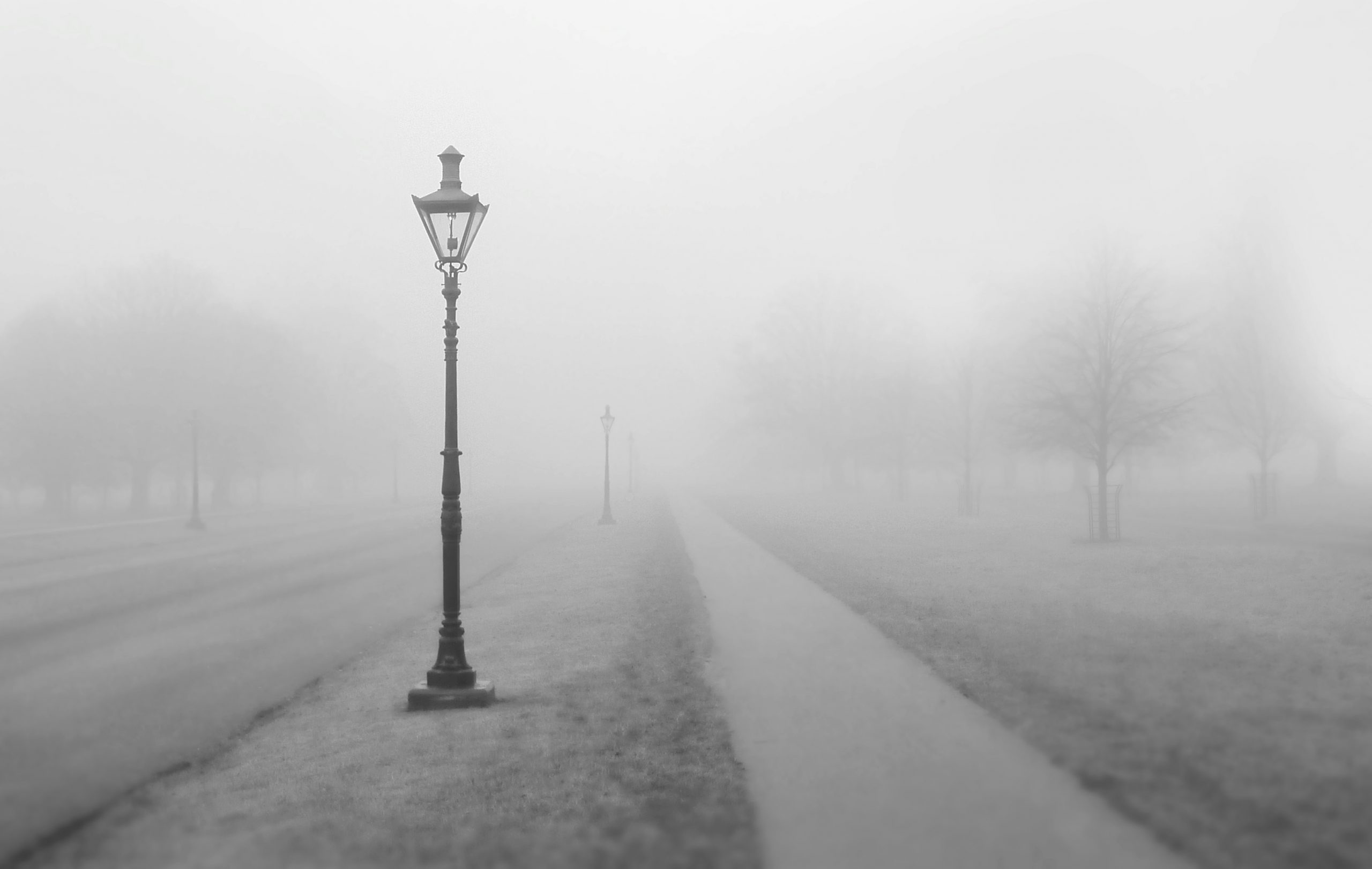 Foggy empty space with a dark street light and an empty sidewalk