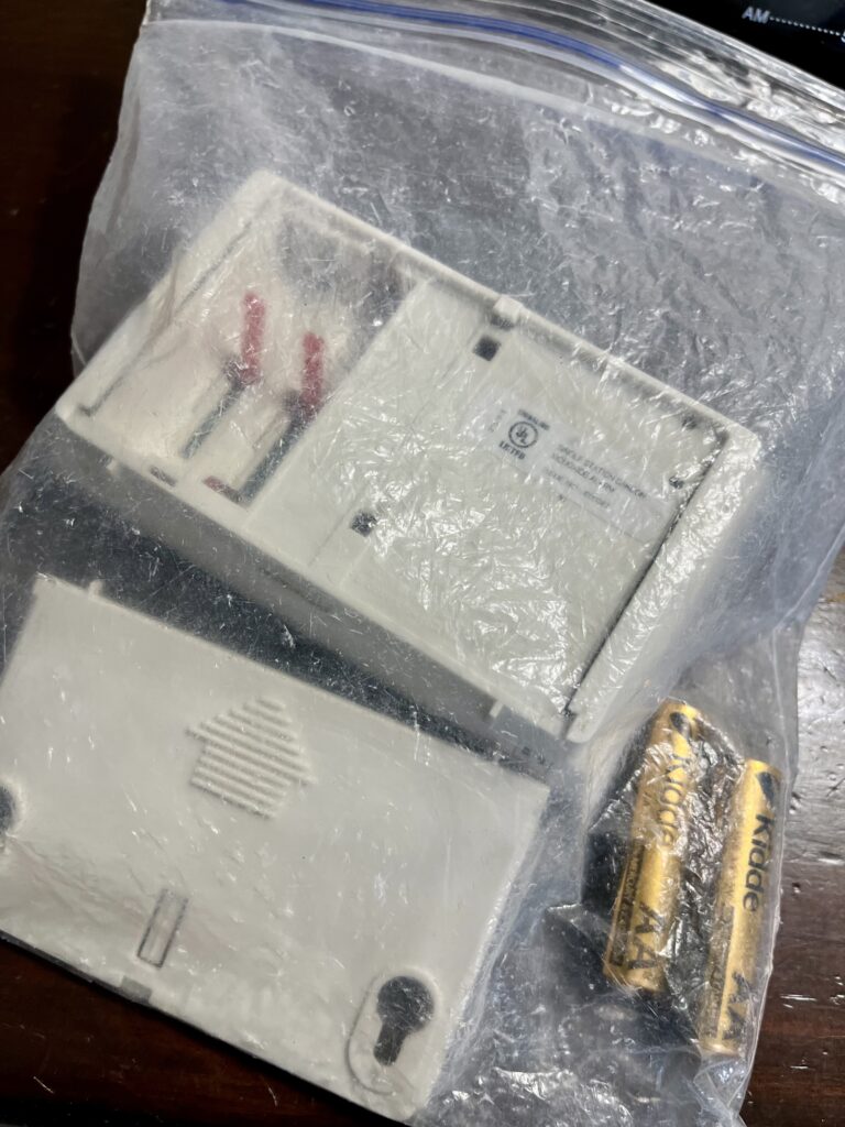 A CO detector disassembled in a ziplock bag for packing and TSA inspection.